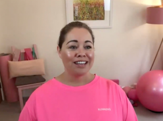 Leanne smiling and speaking to camera in a neon pink top